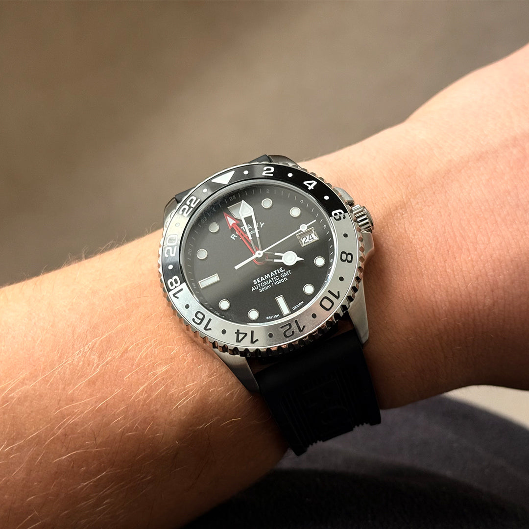Rotary seamatic gmt watch in stainless steel with a black silicone strap. Pictured on a mans wrist