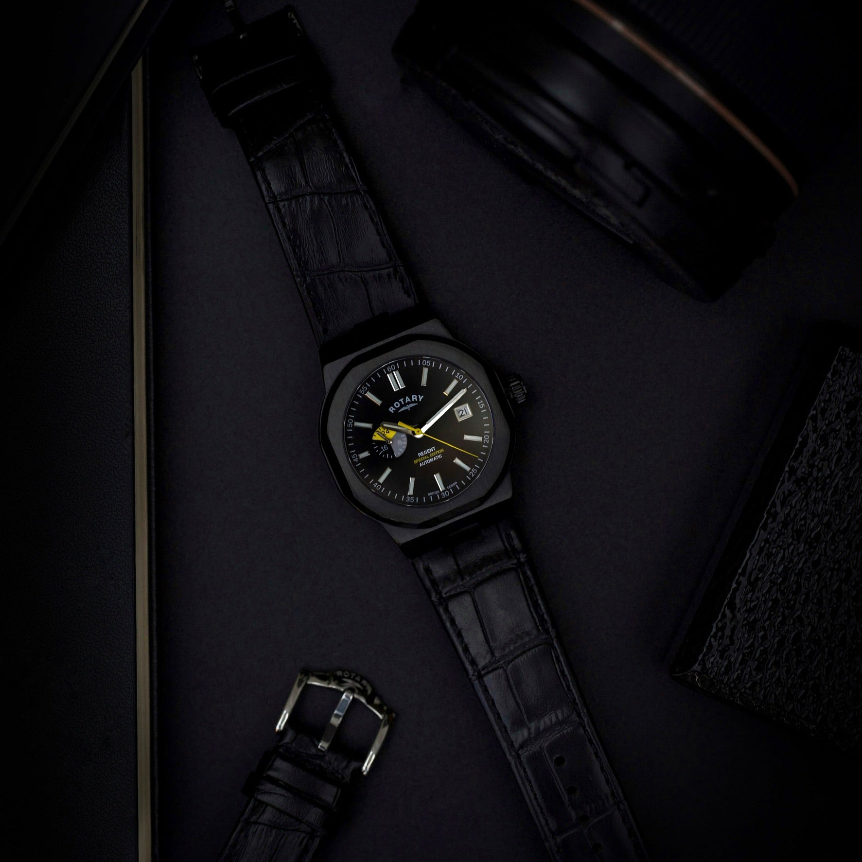 a rotary regent automatic watch lying on a table in a moody setting 
