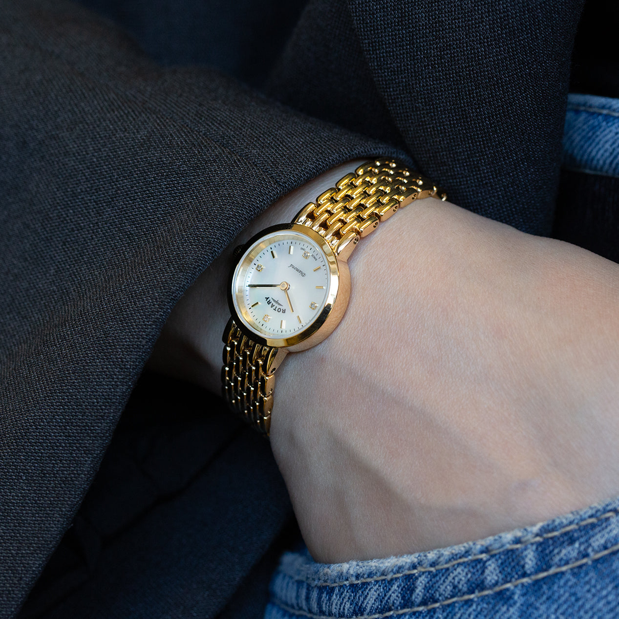 a woman wearing a rotary ladies diamond watch in yellow gold with a mother of pearl dial